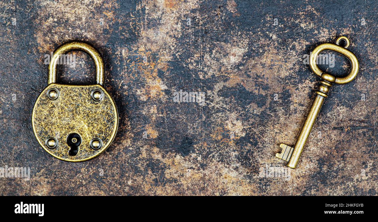 Old vintage key and padlock on a rusty grunge metal background. Escape ...