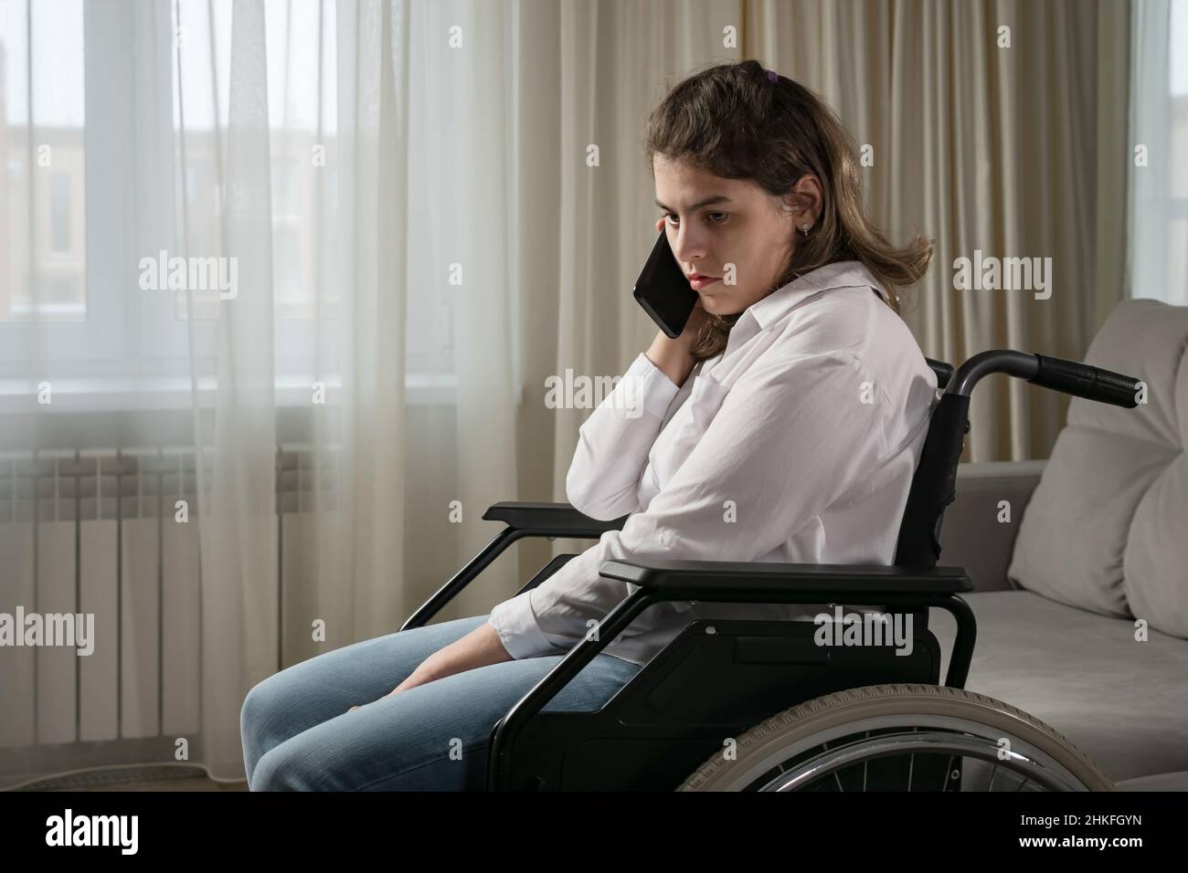 Disabled woman in wheelchair talks on mobile phone at home Stock Photo ...