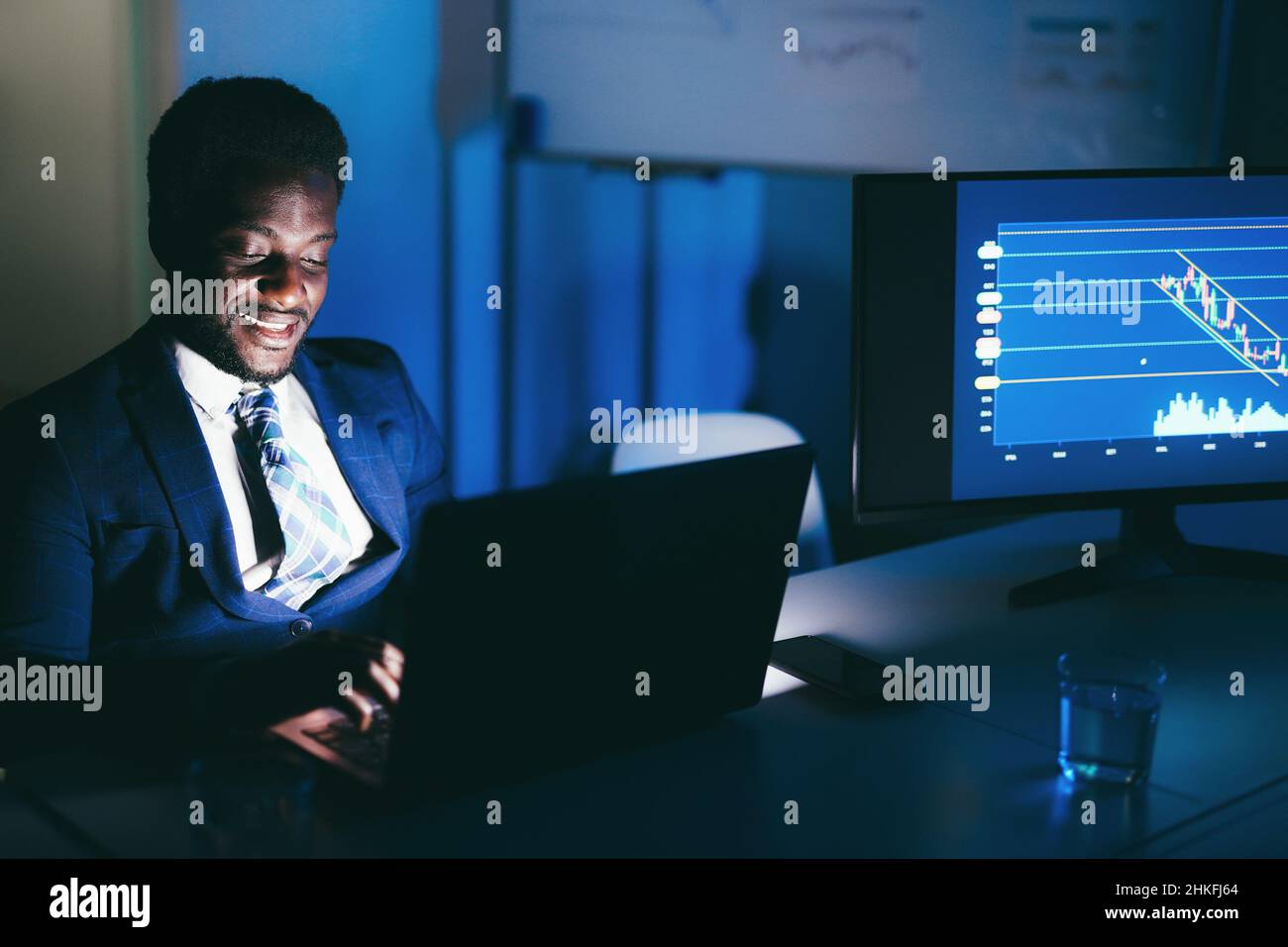 African man trader working at night time inside hedge fund office - Focus on face Stock Photo