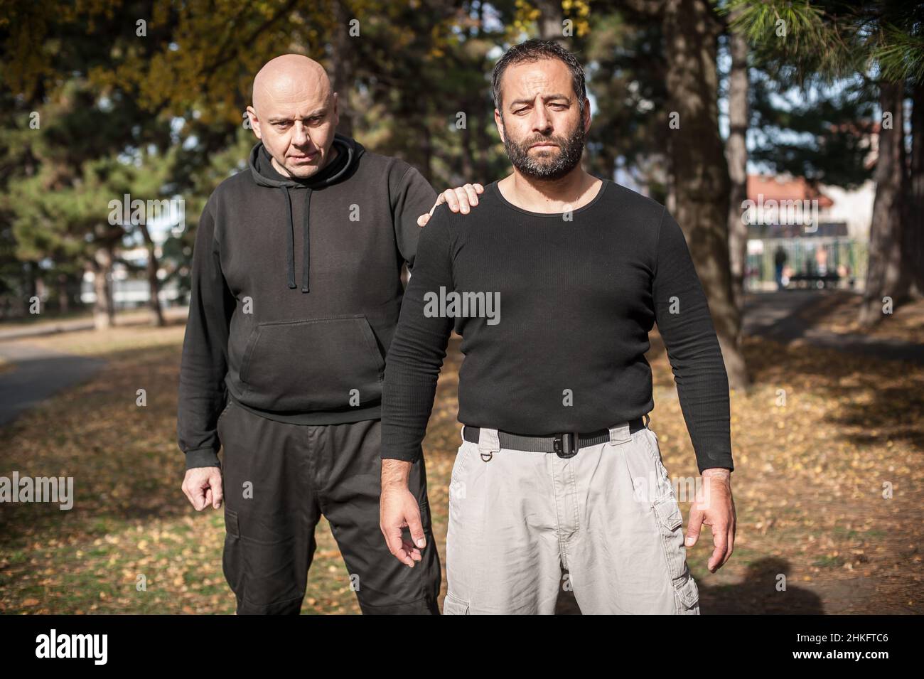Front view of two moody and frowning bully hooligan thugs outdoor in the public park Stock Photo