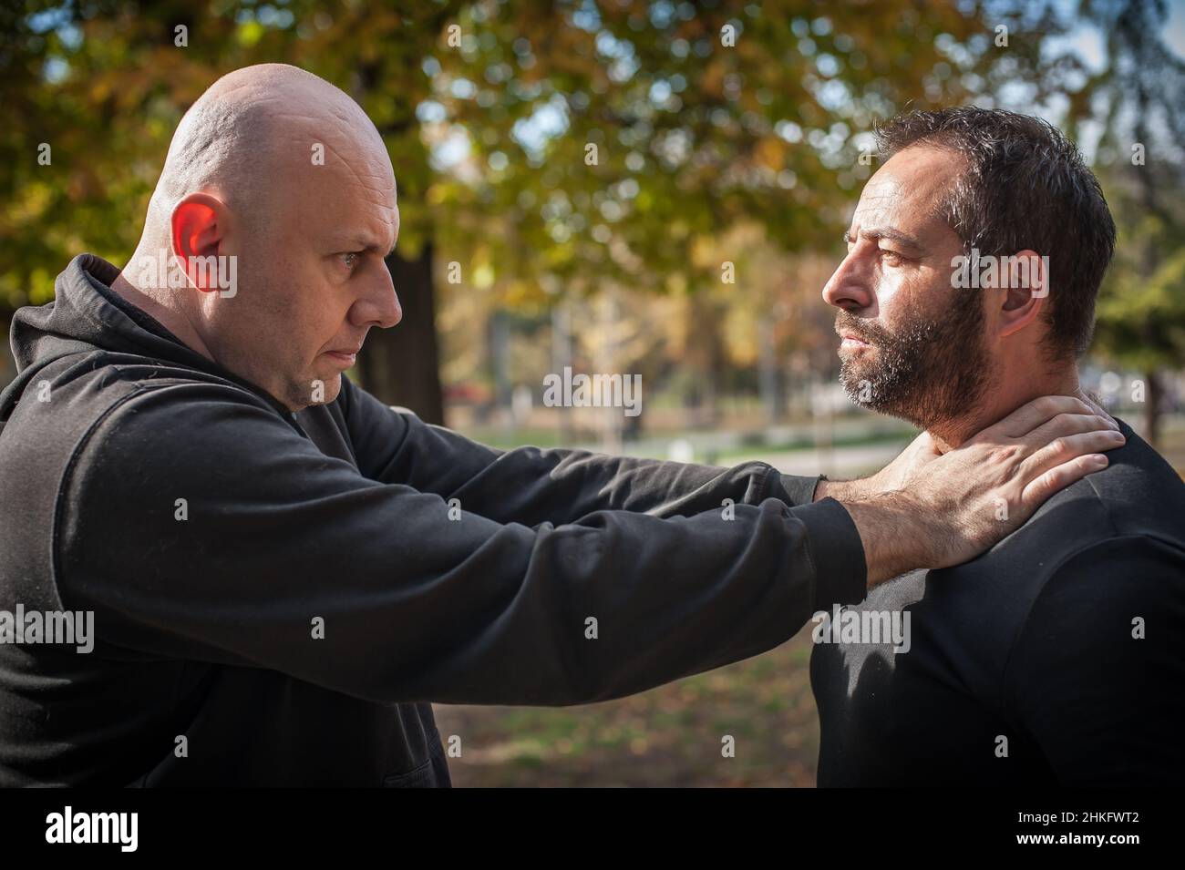 Two men quarrel and fight. Two thugs are fighting. Physical confrontation of people outside on the street Stock Photo