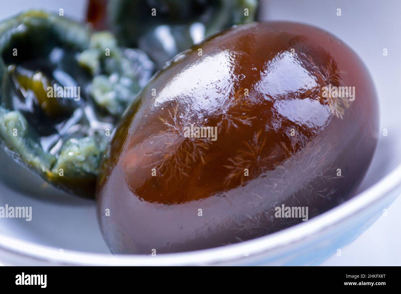 Closeup of Chinese century eggs in white bowl. The egg white is half ...