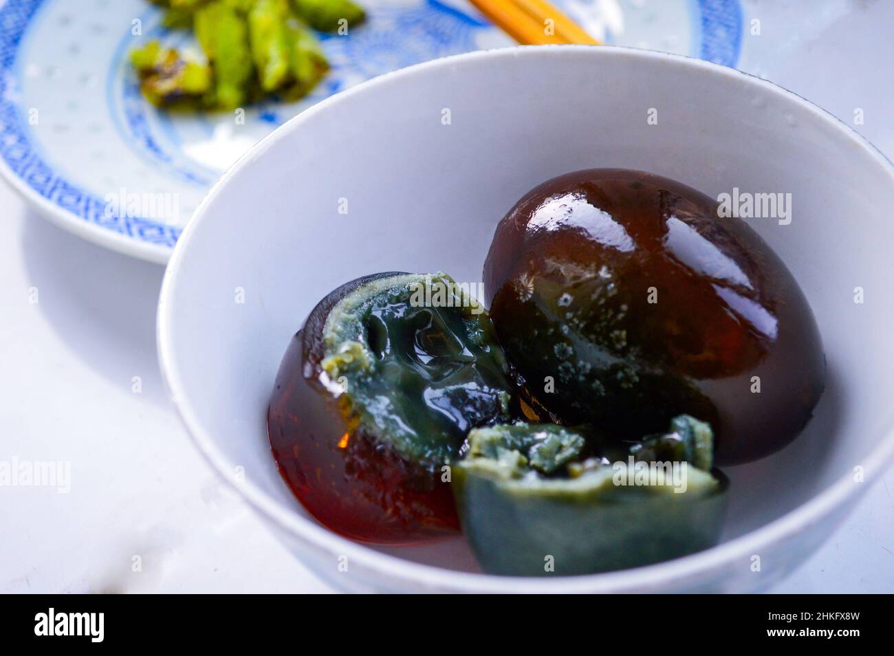 Chinese century eggs in white bowl. One egg cut in half showing black