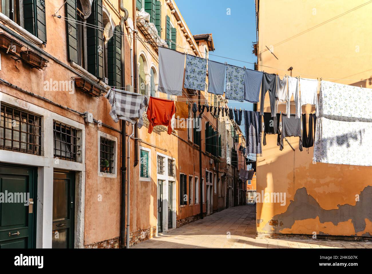 Laundry hanging out of typical Venetian facade,Italy.Narrow street with colorful buildings and clothes dry on rope,Venice.Clean clothes drying outdoor Stock Photo