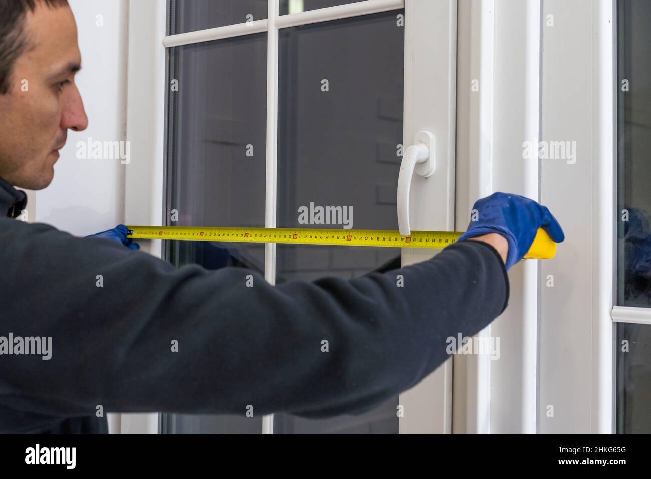 service man installing window with measure tape Stock Photo