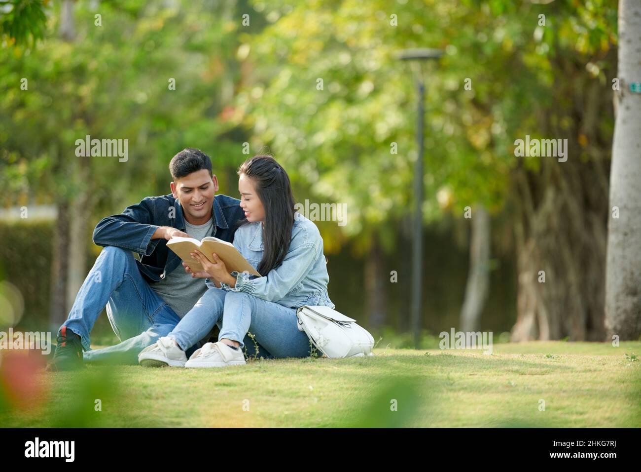 Friends spending time on college campus and reading book together Stock Photo
