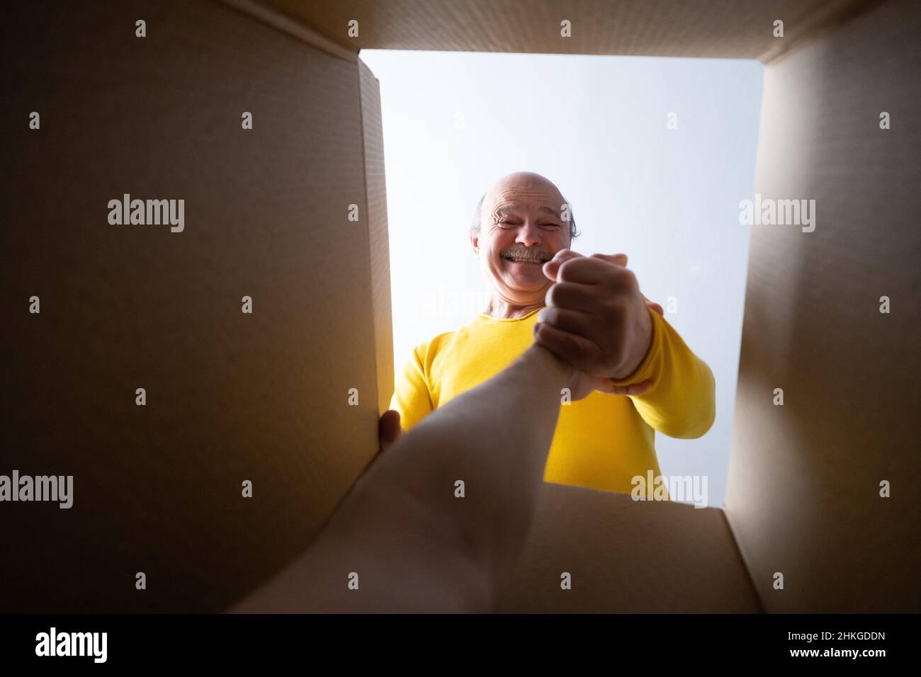 Senior manhelping somebody to get out from box. Help in strange situation. Stock Photo