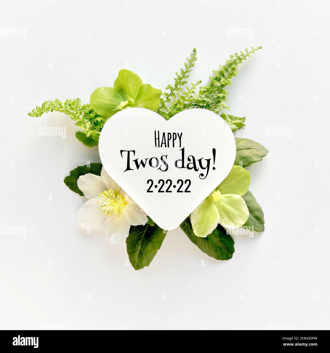 Happy Twos day 2.22.22 or Twosday. Winter flower arrangement. White paper heart with greeting text. Stock Photo