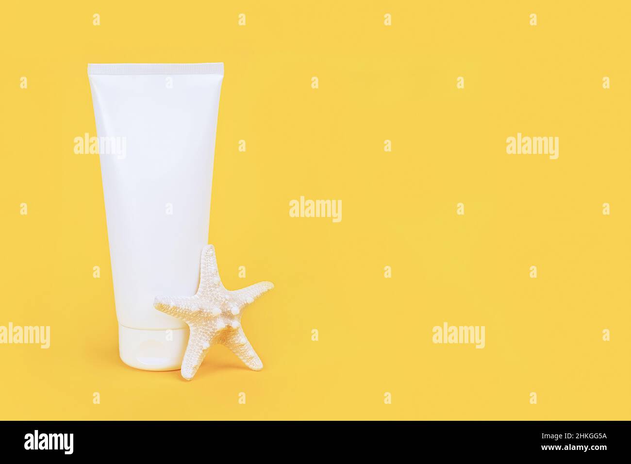 White blank cosmetic tube with sunscreen, suncream for face or body and starfish on yellow background. Concept skin care in summer holiday Mockup Fron Stock Photo