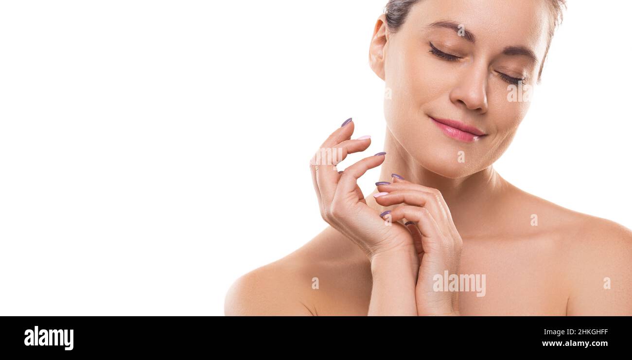Close-up portrait of a 40 years old woman with closed eyes and clean skin natural makeup isolated on white background. Woman touching her skin. Photo Stock Photo
