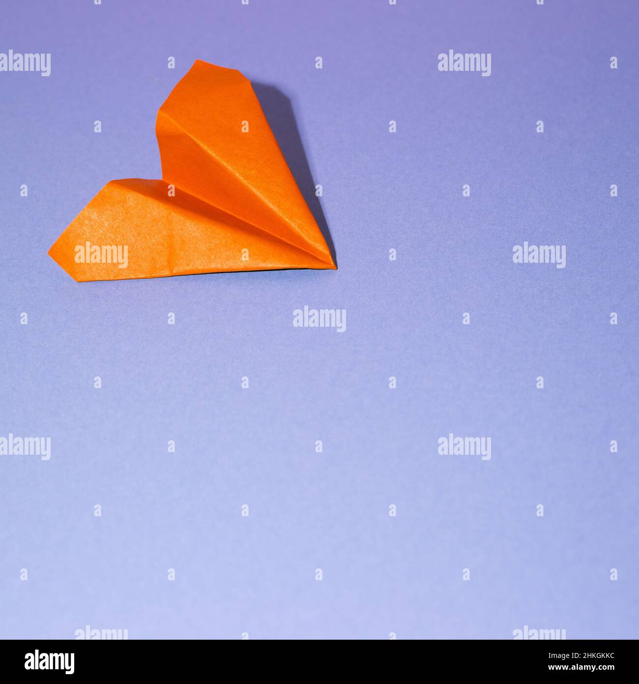 Orange paper airplane on blue background. copy space Stock Photo