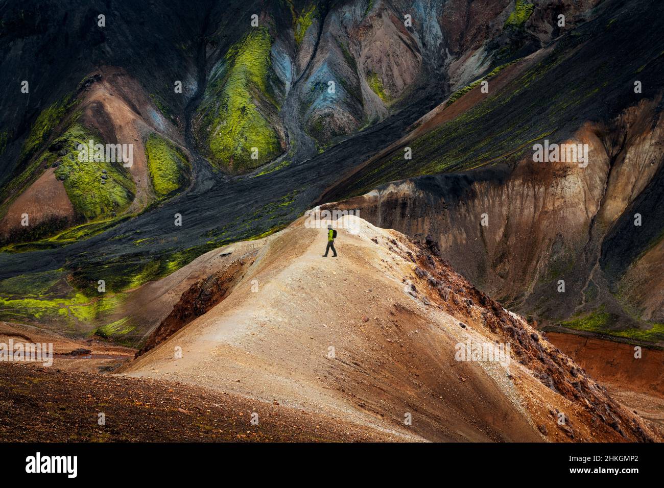 Hiker in front of colourful mountains in Landmannalaugar. Stock Photo