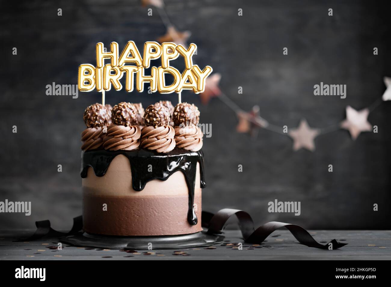 Chocolate birthday cake with  chocolate ganache drip icing and happy birthday banner Stock Photo