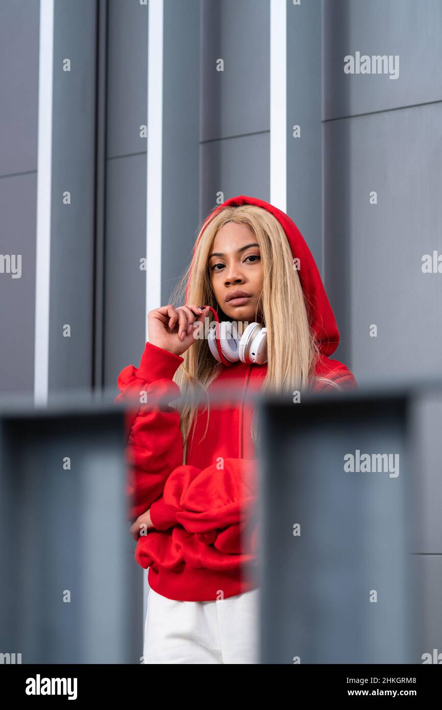 Cheerful African American woman with long blonde hair wearing sportswear and wearing headphones Stock Photo