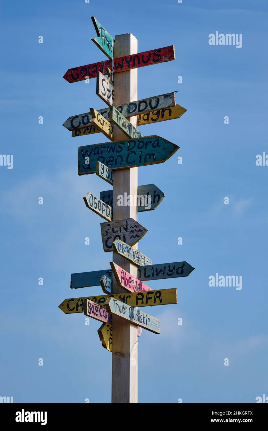 A colourful wooden signpost points out local landmarks in all directions from Porth Dinllaen, Wales Stock Photo