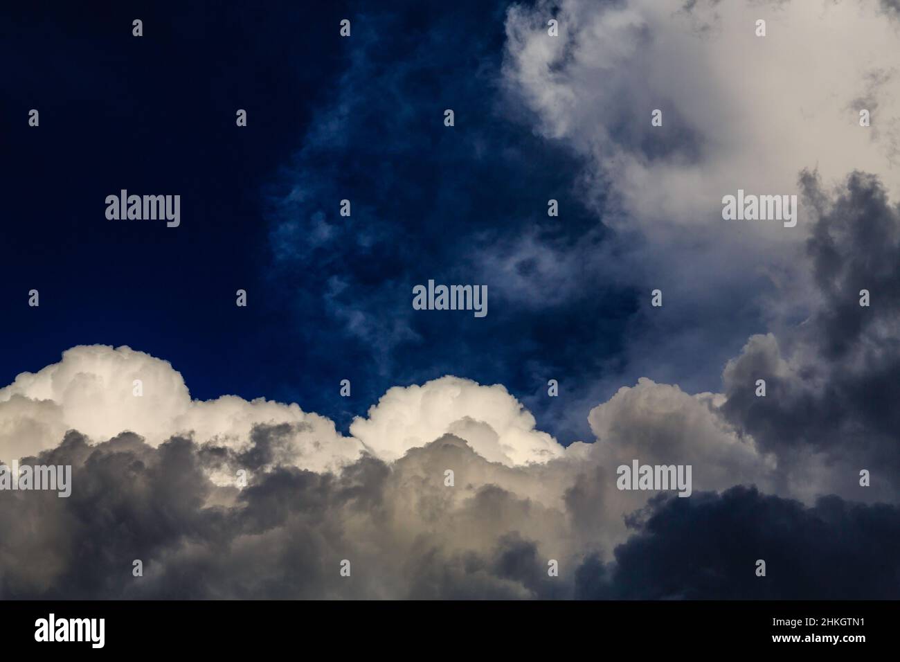 Vivid, uniquely-framed cloudscape in a conflicted sky of overlapping blues, whites and greys. Stock Photo