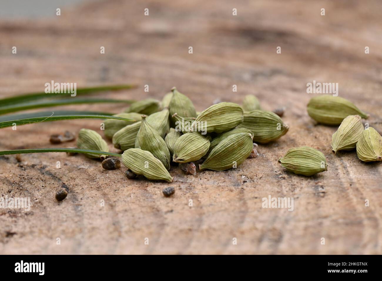 closeup the bunch green ripe cardamom with green leaves over out of focus wooden background. Stock Photo