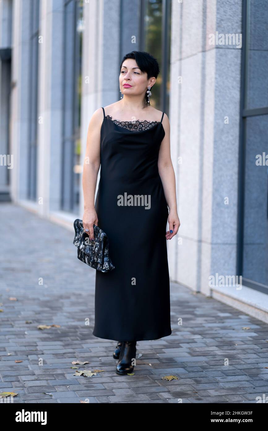 Elegant woman in a stylish black dress posing on a city street Stock ...