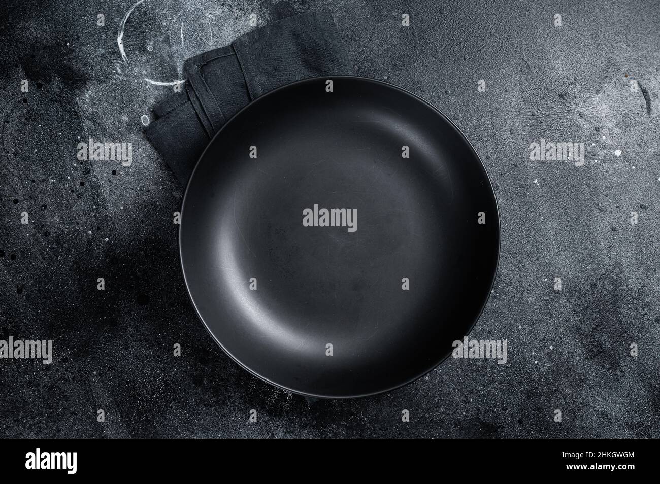 Empty black craft plate on table. Table setting. Black background. Top view. Copy space Stock Photo