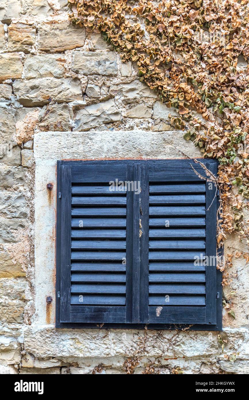 An ancient window with blue shutters on the stone wall of the house ...