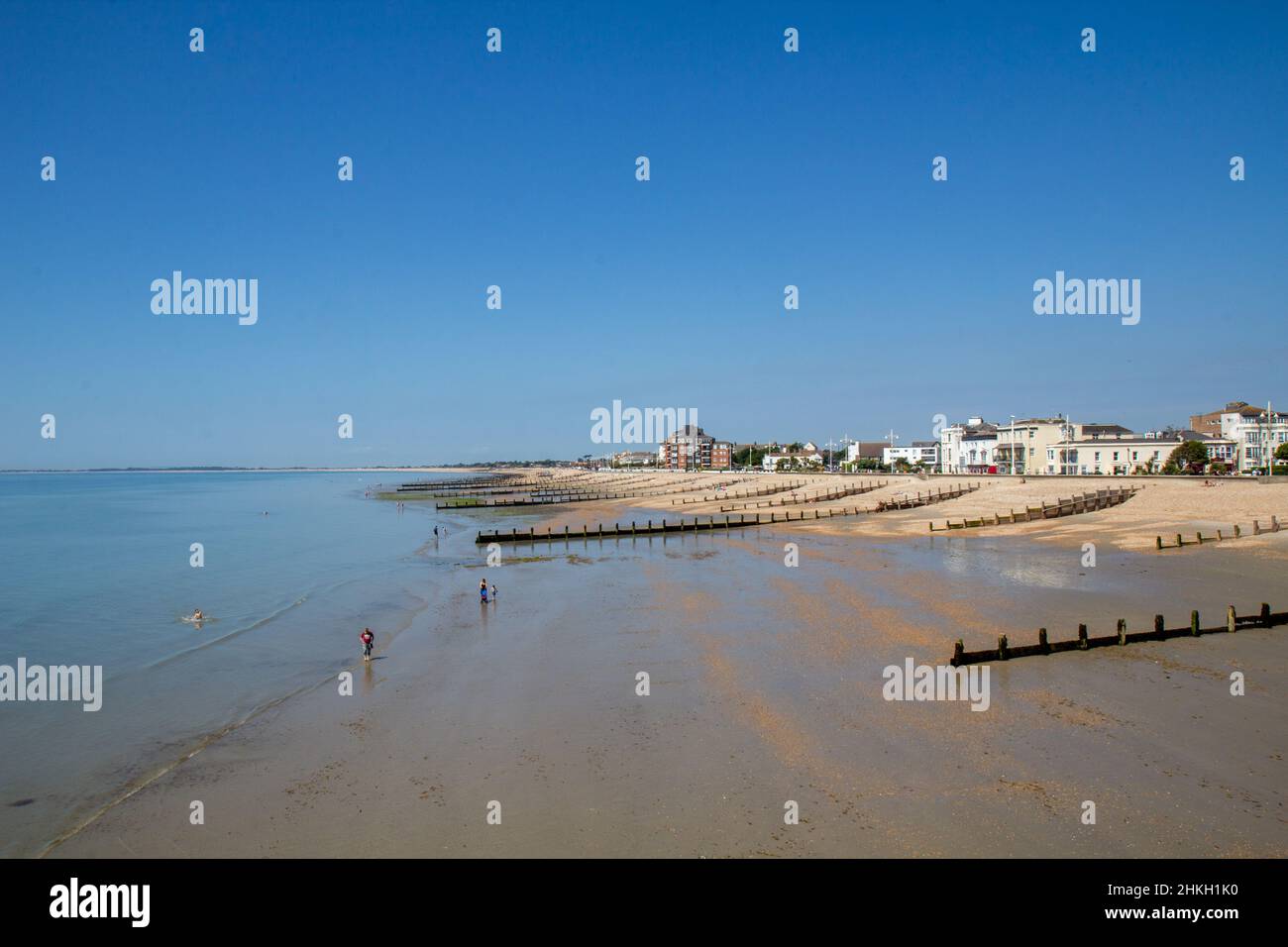 Bognor Regis beach high up looking west from the pier at low tide with clear blue sky and expances of sand. Stock Photo