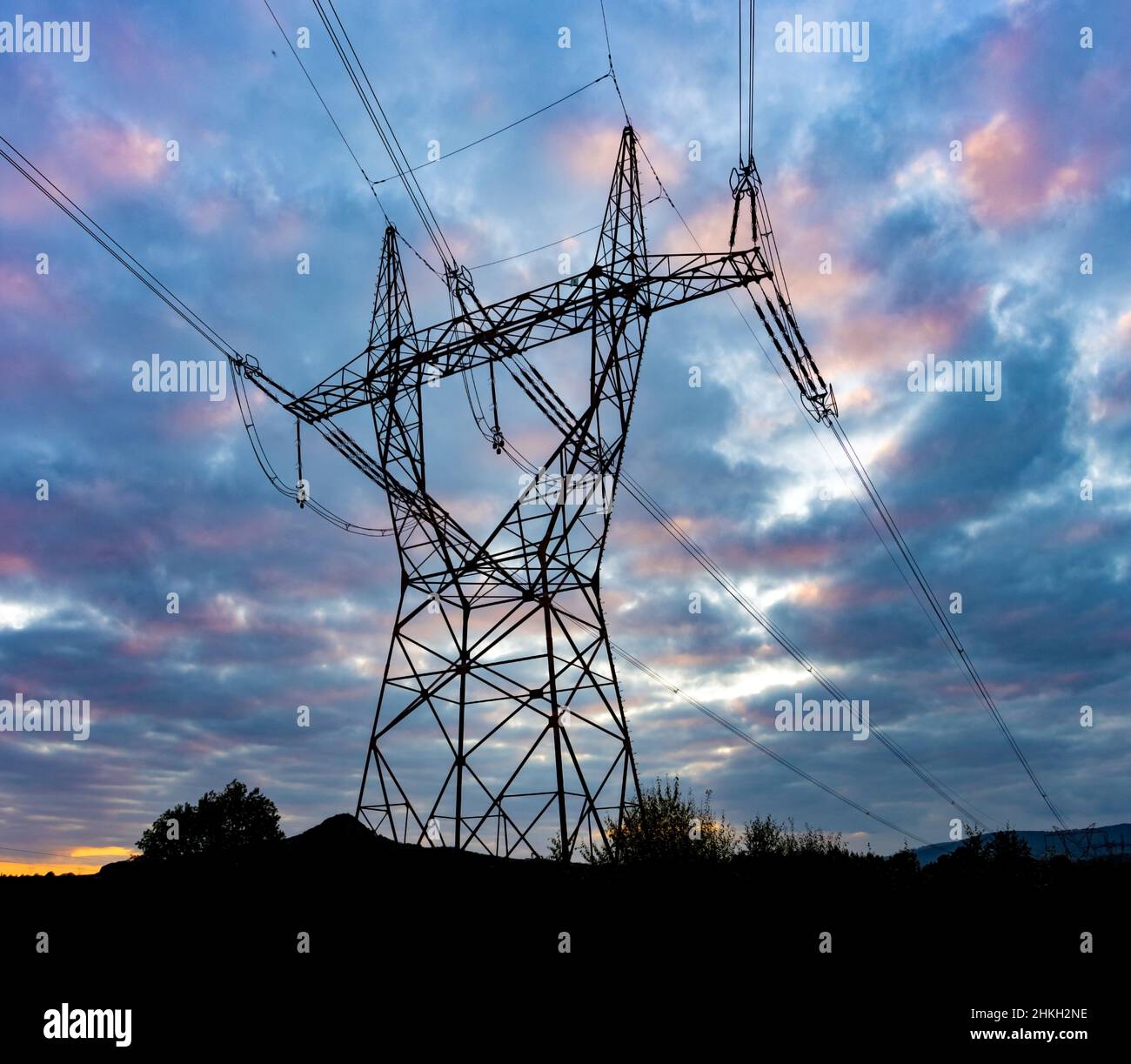 Silhouette of a high voltage tower with the clouds at sunset on a ...