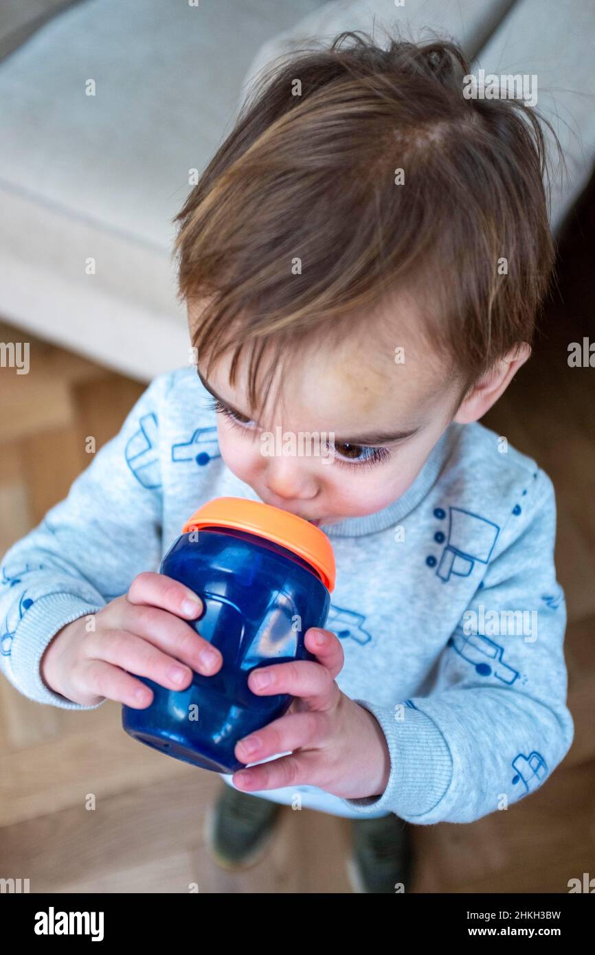 Young 2 year old boy enjoying a healthy drink of water from a beaker Stock Photo