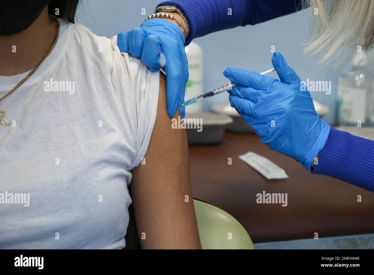 A NHS vaccinator, administers the Pfizer Covid-19 booster jab to woman, at a vaccination centre. Stock Photo