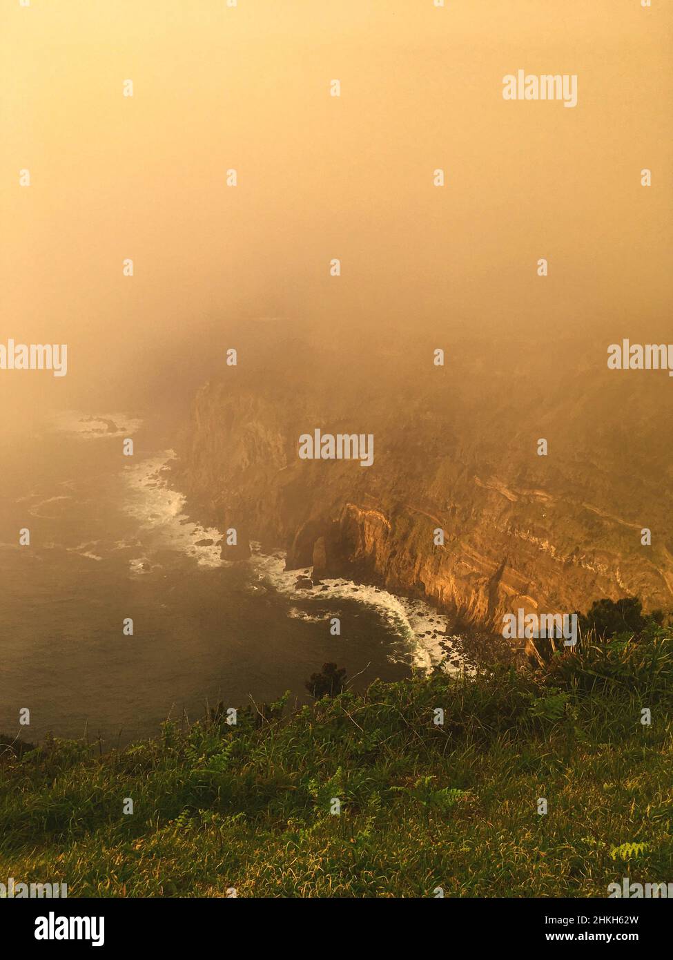 Misty sunset scenery of sea and high cliffs Stock Photo