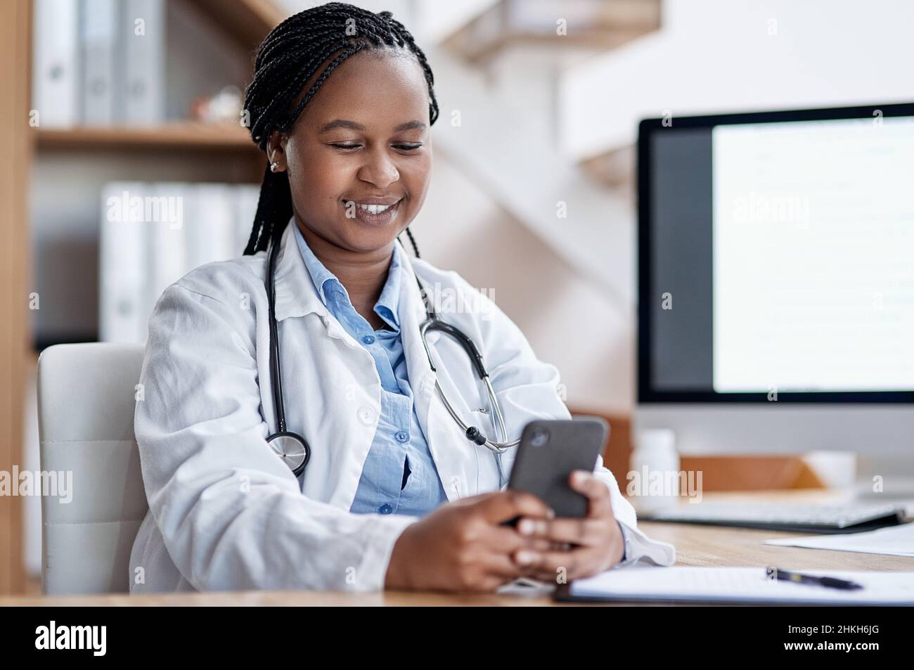 She welcomes texts from her patients. Shot of a young doctor using a cellphone while working in her office. Stock Photo