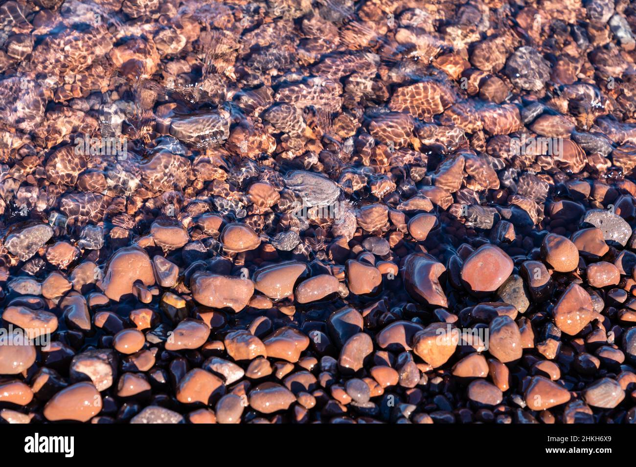 Abstract view of pink rocks and agates with water as a wave comes in. Taken at Hunters Point Park in Michigan Stock Photo