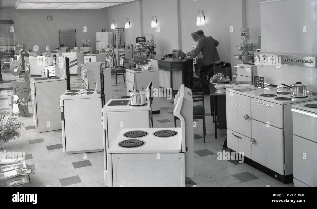 1960s, historical, interior view of a new electrical appliance showroom and shop of Southern Electricity Services, Witney, Oxford, England, UK, showing the range of household appliances available, including the latest electric cookers. A promotional card on display, has the message 'get up todate, go electric'. A lady and gentleman stand at an area with a till. Brands of the day include Hotpoint, Kenwood and Electrolux, with the newly relased Electrolux 65 vacum cleaner. Stock Photo