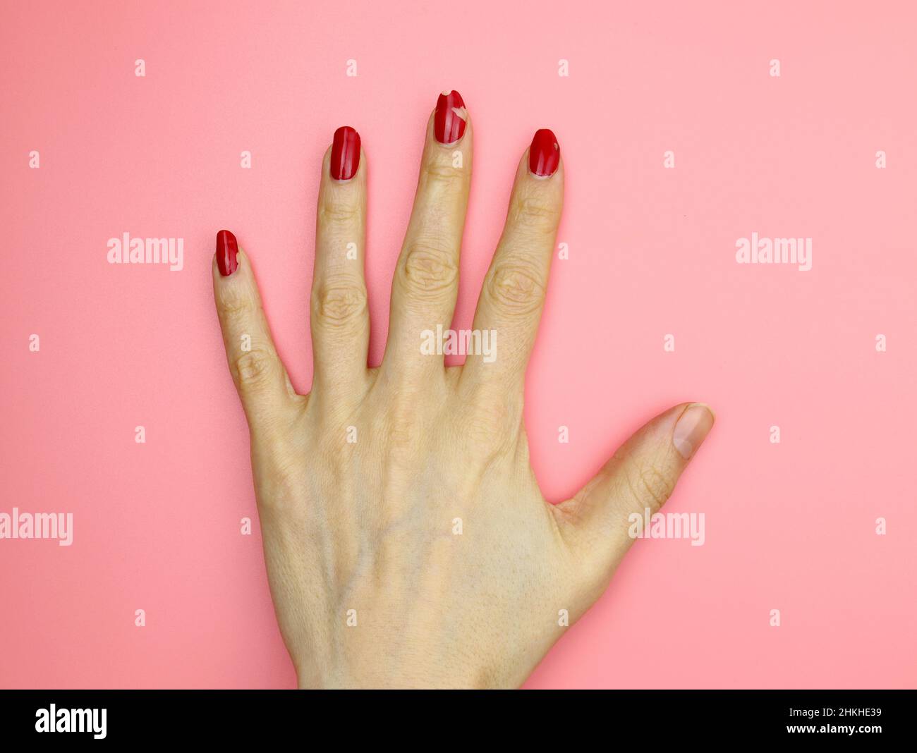 Peeling nail polish. Girl's hand with red nail polish without manicure