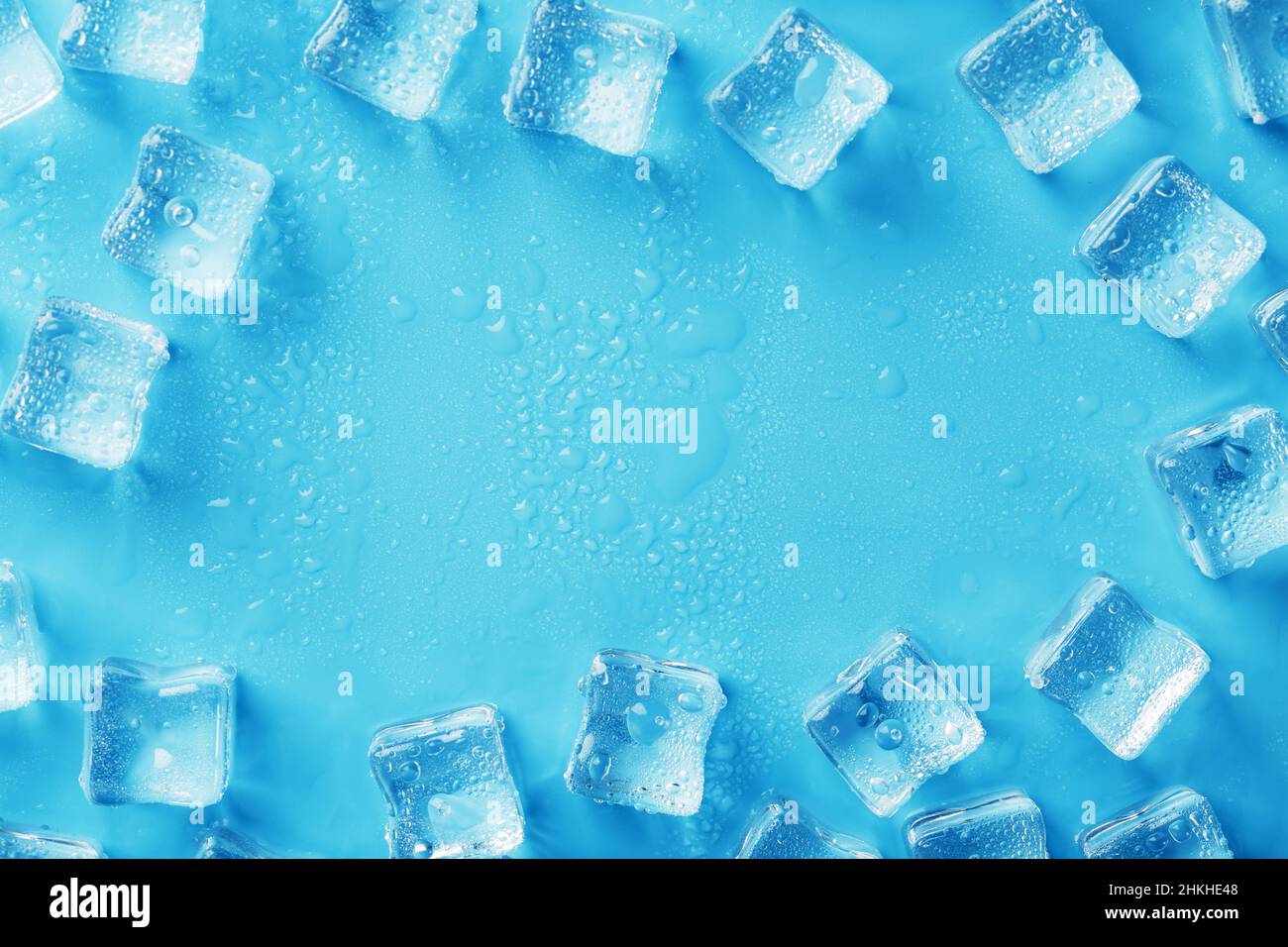Ice cubes with water drops scattered on a blue background, top view ...
