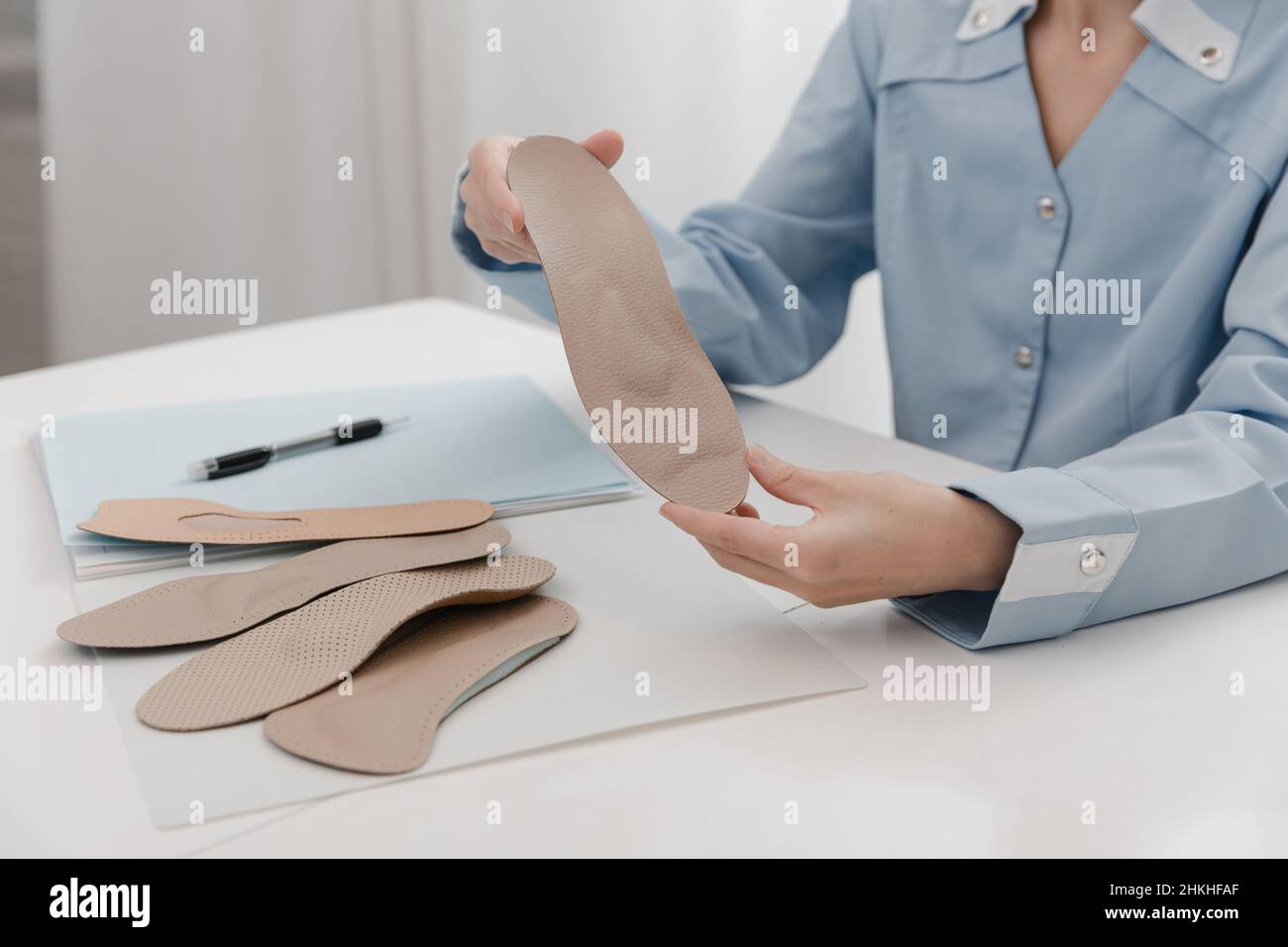 Doctor holding an insole while sitting at a table. Orthopedist tests the medical device. Orthopedic insoles. Foot care. Flat Feet Correction Stock Photo