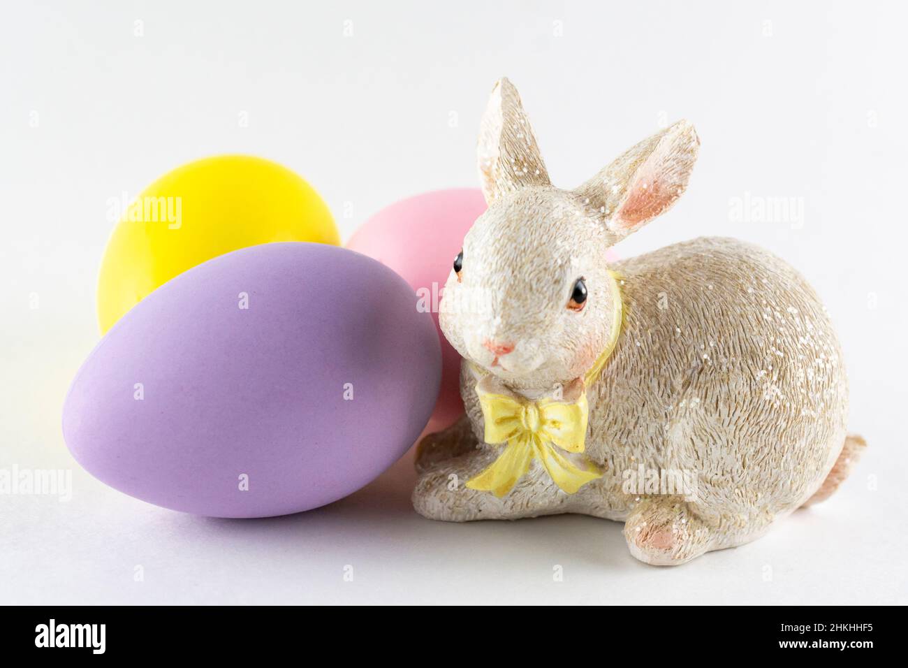 Easter bunny figurine with three Easter eggs on white background.  Close up view. Stock Photo