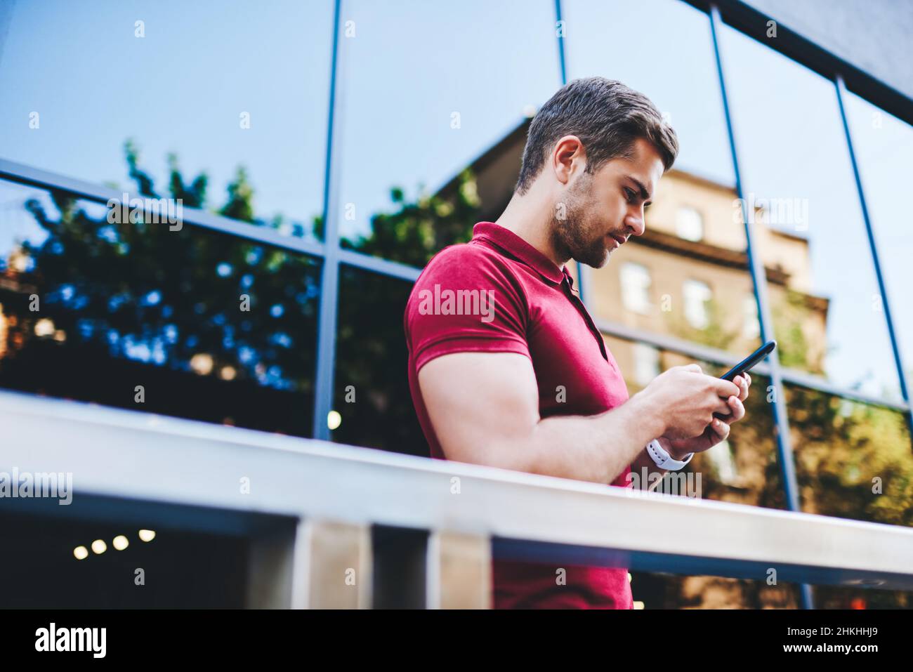 Concentrated young man messaging using mobile phone Stock Photo