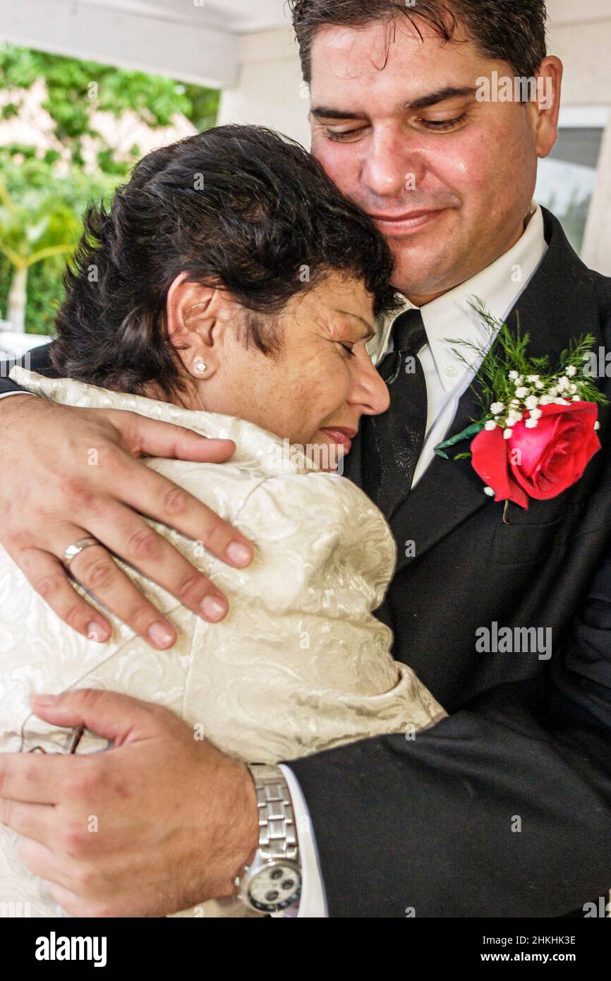 Miami Florida,wedding event marriage Jehovah's Witness,Hispanic man woman Cuban family groom mother son hugging Stock Photo