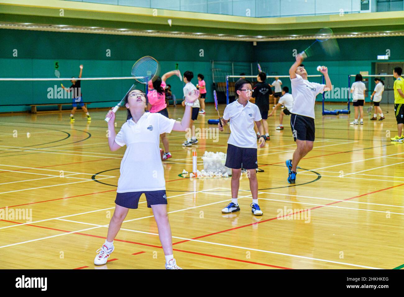 Hong Kong Chinese Island,Hong Kong Park Sports Centre,center,badminton courts indoor gymnasium,Asian boys girl female students practicing serving Stock Photo