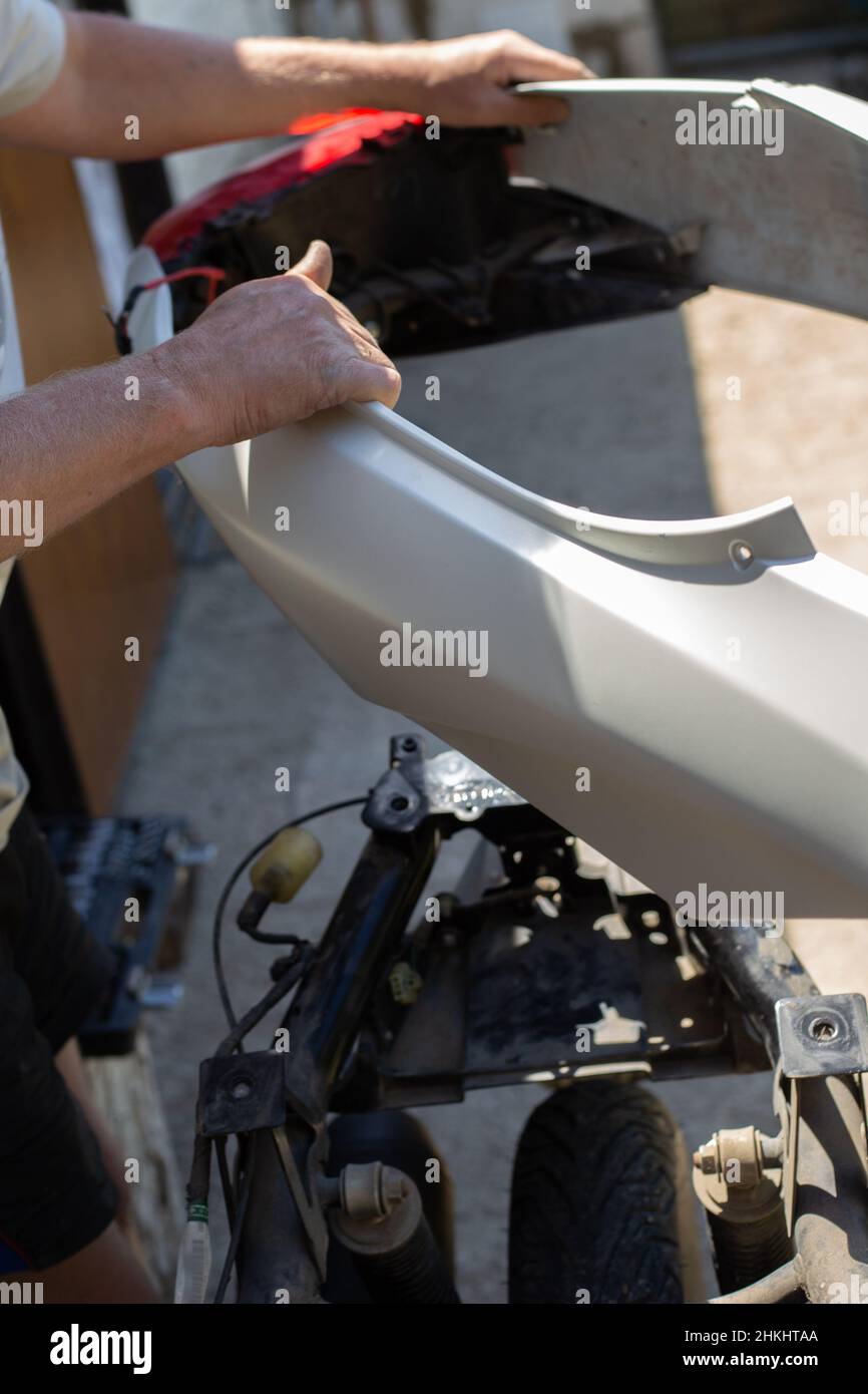 A man disassembles a motorcycle for repair, removes the body kit of a motorbike. Stock Photo