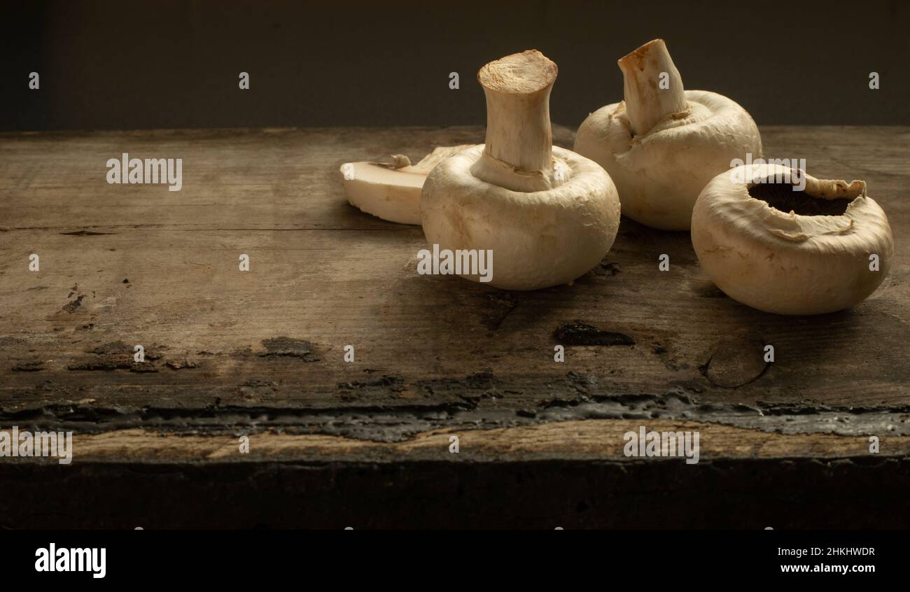 Close up still life of three mushrooms on a rustic wooden table Stock Photo