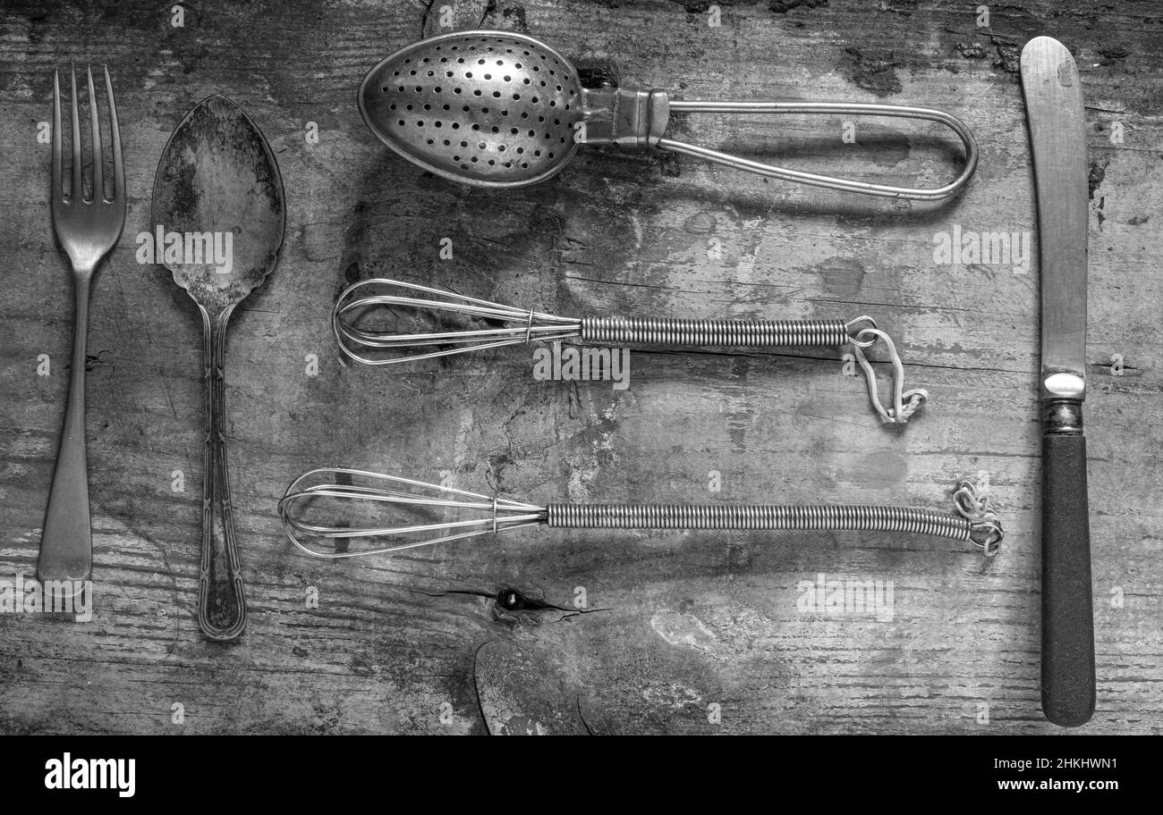 close up antique old fashioned kitchen utensils  on a rustic background from above photographed in black and white Stock Photo