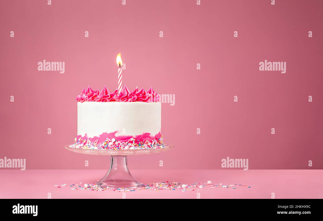 Birthday Cake with pink buttercream icing, colorful sprinkles and lit ...