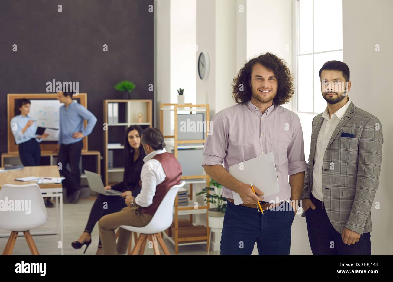 Two young office colleagues smiling at the camera, holding documents Stock Photo