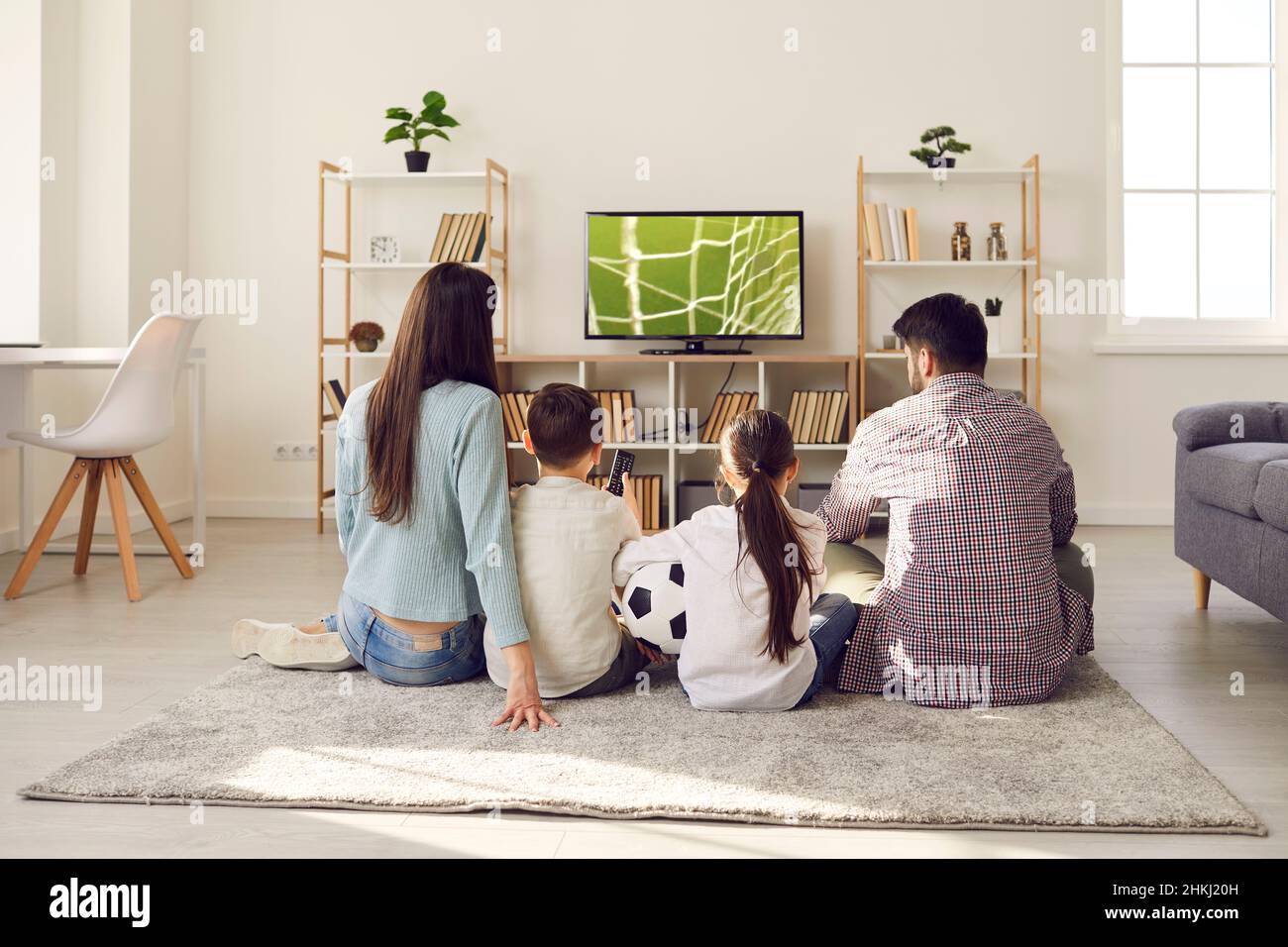 Family with children watching football match together at home cheering for their favorite team. Stock Photo