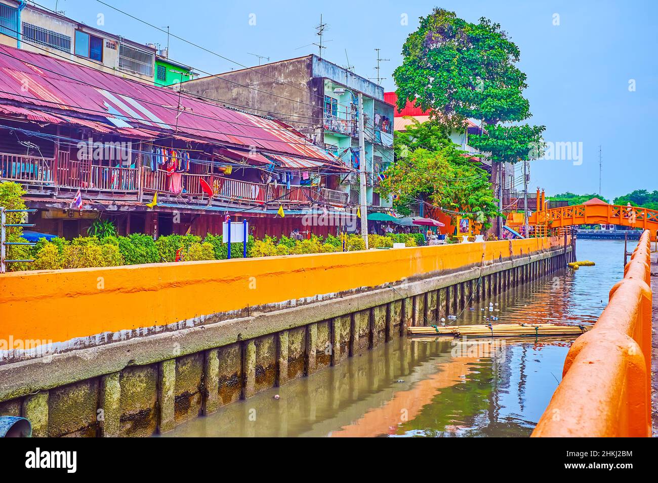 The shabby houses in  residential district and narrow canal with a orange bridge, Bangkok, Thailand Stock Photo