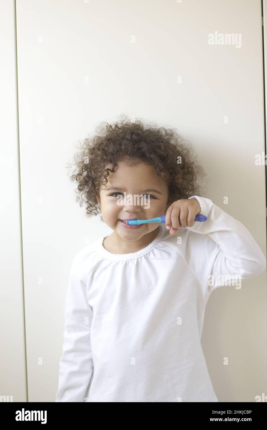 Girl bushing teeth with blue toothbrush Stock Photo Alamy