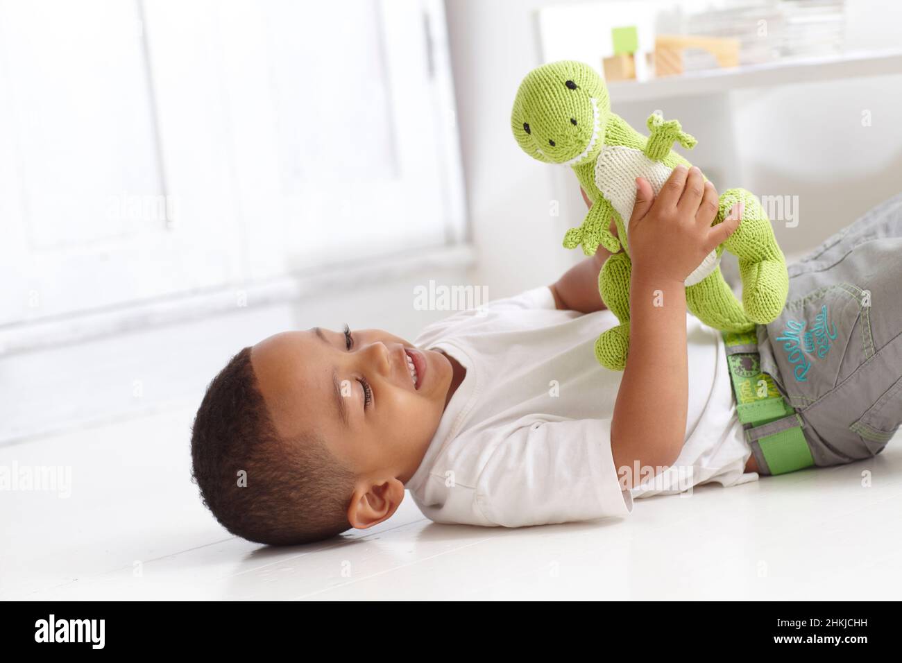 Boy playing with knitted dinosaur toy Stock Photo