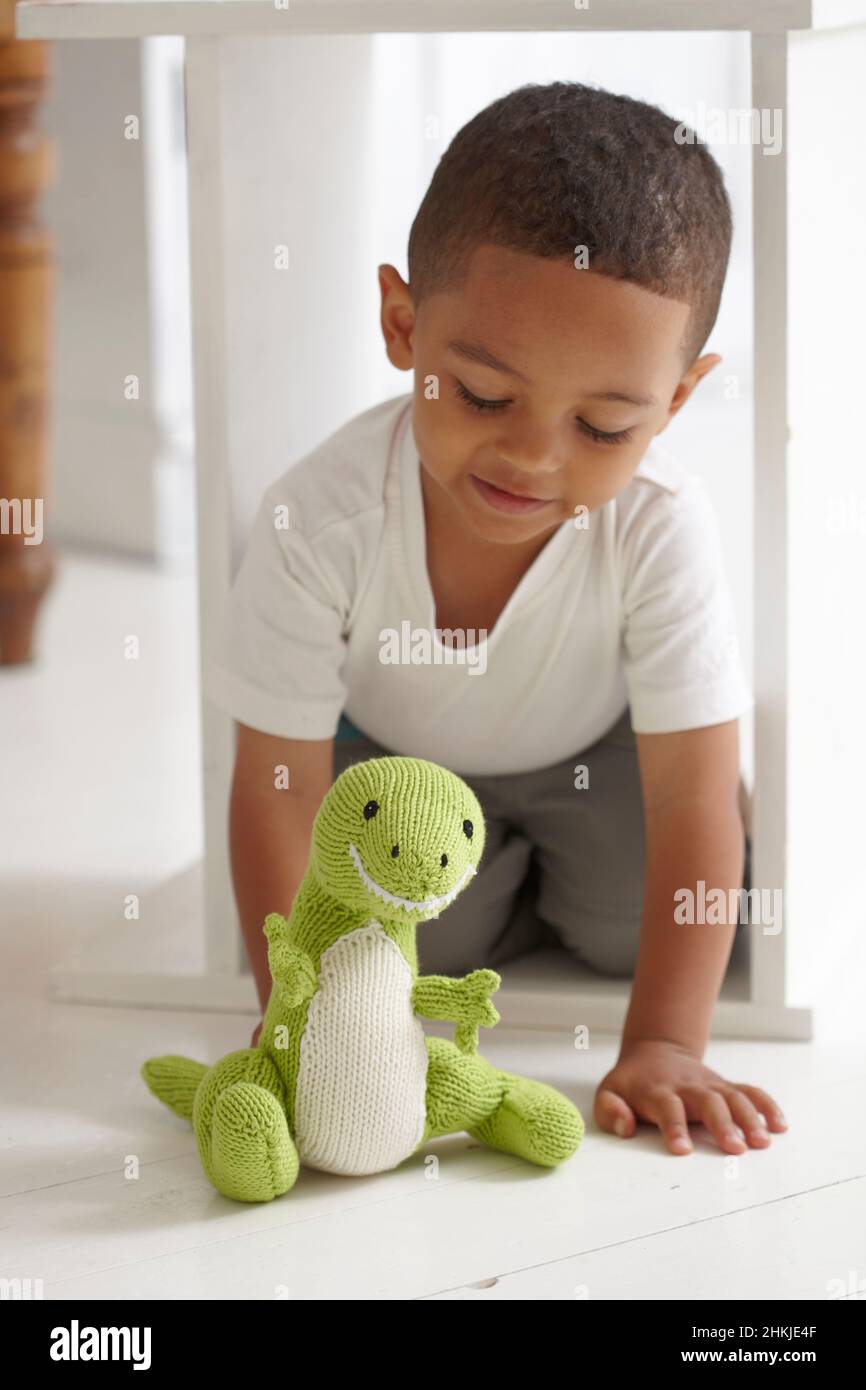 Boy playing with knitted dinosaur toy Stock Photo