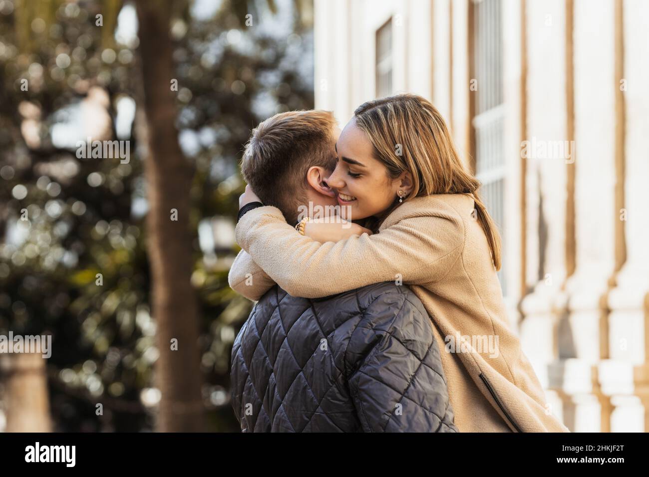 a smiling young woman hugs her boyfriend intensely Stock Photo